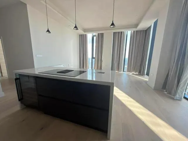 Kitchen island with a white worktop and inset hob beside the open-plan living area.