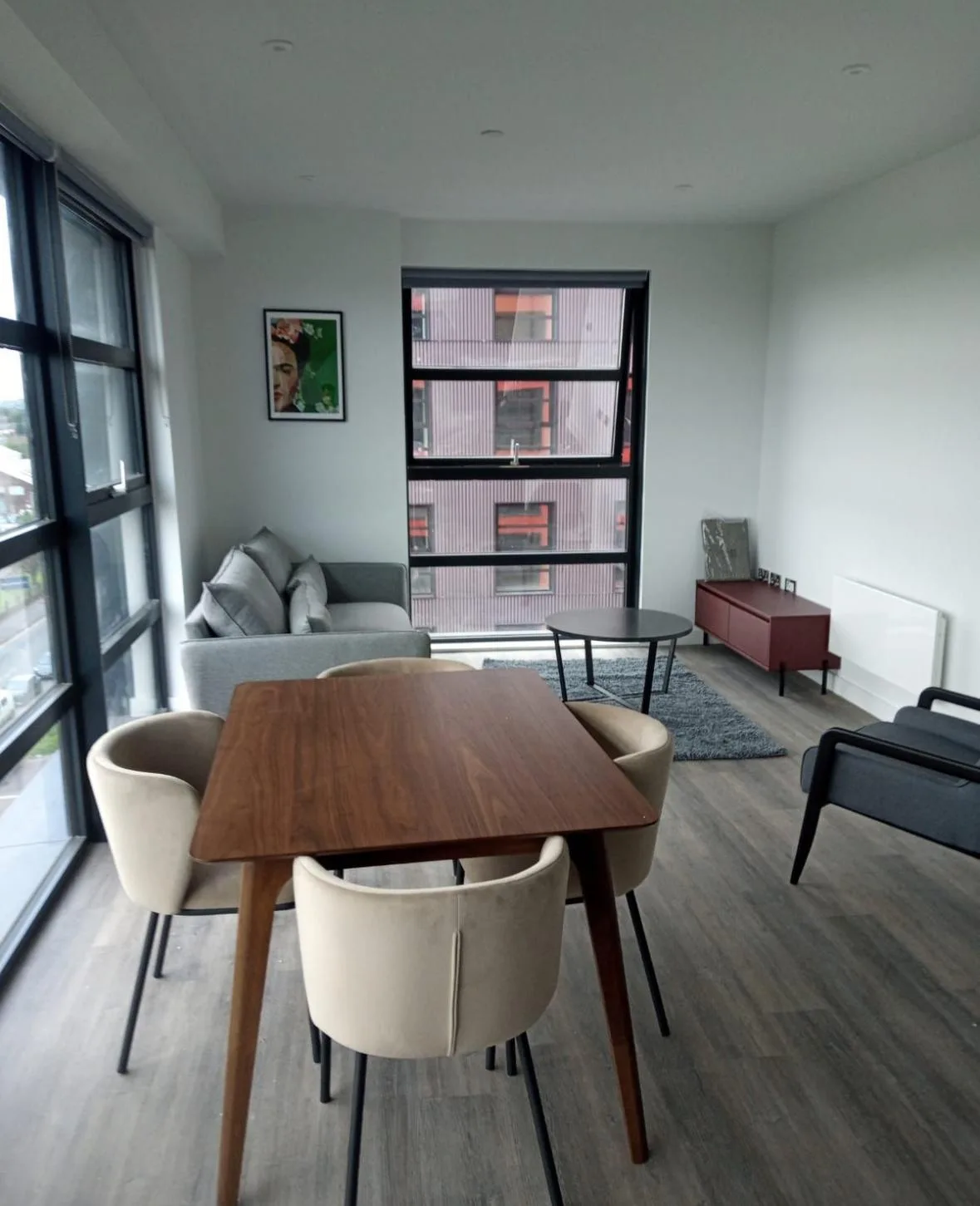 Dining table and chairs beside full-height windows.